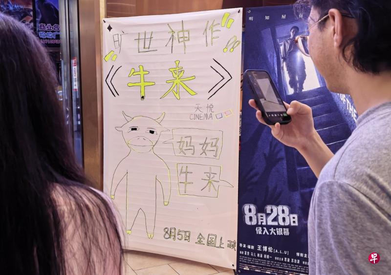 平台数据显示，截至星期天（8月23日），中国电影《牛来》累计票房已突破4200万元人民币（793万新元），观影人次超过150万。图摄于8月21日晚，北京市朝阳区一家电影院入口处摆放有电影《牛来》的手绘海报。（中新社）
